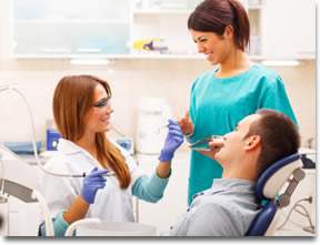 A dentist and her assistant smiling